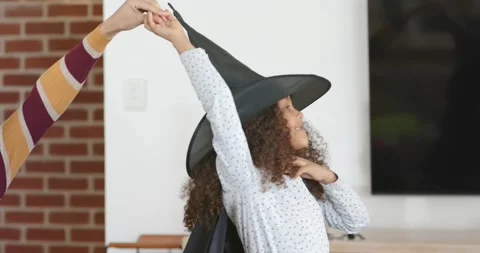 African American mom reaching left guiding Youth girl in witch hat, cape at home Stock Footage 345086941