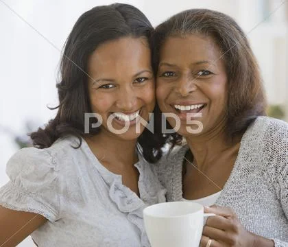 African American mother and adult daughter hugging Stock Photos