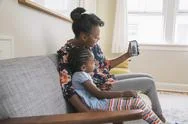 African American Mother And Daughter Video Chatting On Cell Phone Stock Photos