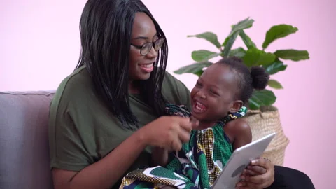 African american mother using tablet with her little daughter on couch at hom Stock Footage 137717622