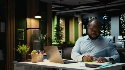 African american office worker placing a sticky note on his laptop as a reminder Stock Footage 320032079