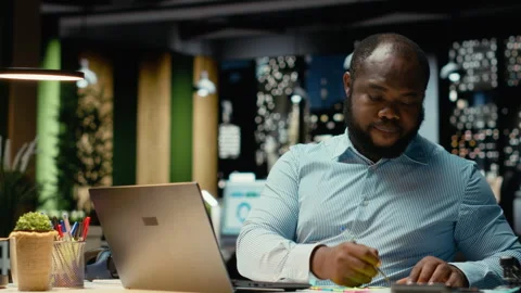 African american office worker placing a sticky note on his laptop as a reminder Stock Footage 320090422