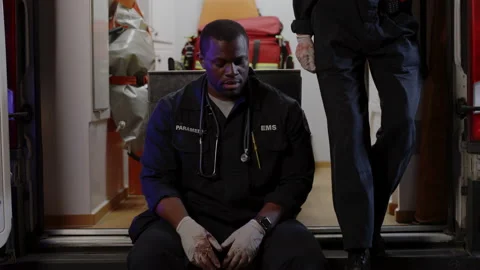 African american paramedic feeling down while sitting in ambulance Stock Footage 164730008