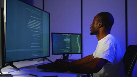 African American programmer coding on multiple screens at night Stock Footage 305009217