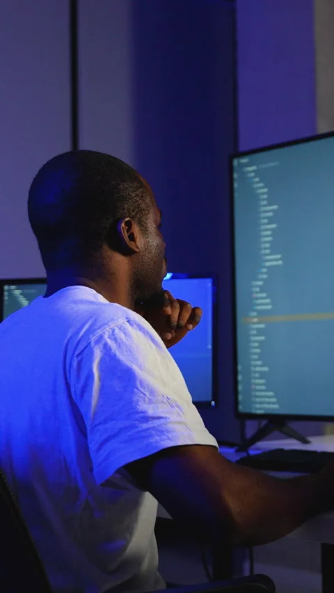 African American programmer coding on multiple screens at night Stock Footage 305022757