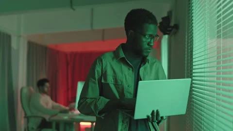 African-American Programmer Standing with Laptop in Dark Room Video stock 165219781