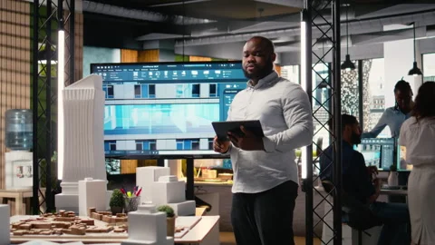 African american real estate developer reviews city planning layout on laptop Stock Footage 316795451