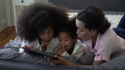 African american single mom with two daughter lying down on bed looking table Stock Footage 136739897