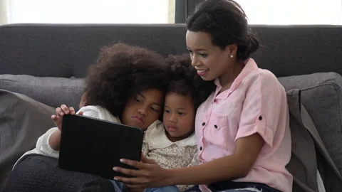 African american single mom with two daughter lying down on bed looking table Stock Footage 136741945