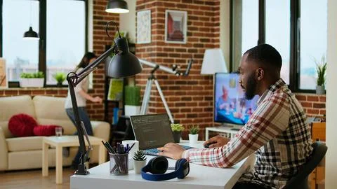 African american software developer works on programming code on a laptop 스톡 사진
