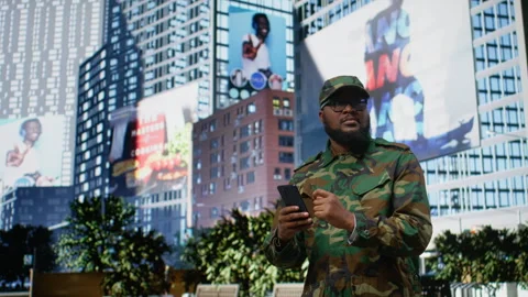 African american soldier in uniform using a mobile phone on a city street Stock Footage 323886328