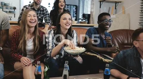 African American sports fans celebrate win at home. Passionate supporters shout Stock Photos
