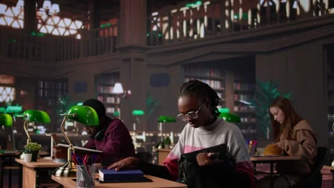 African american student comparing class notes with data from the library Stock Footage 308727010