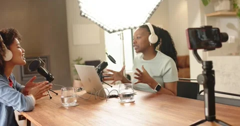 African American studio cohosts tapping laptop speaking into mics laughing Vídeo Stock 344850741