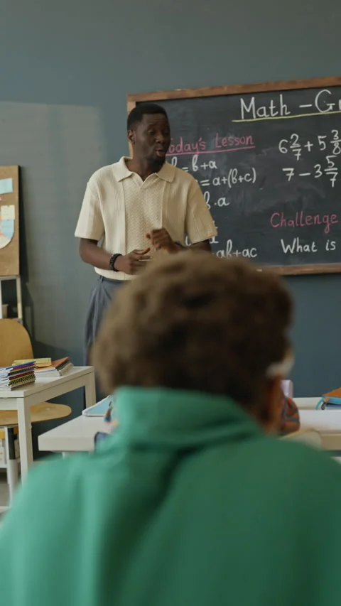 African American Teacher Explaining Math Equations on Blackboard to Students Stock Footage 340551360