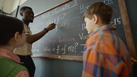 African American Teacher Explaining Math Equations to Children at Blackboard Stock Footage 340552522