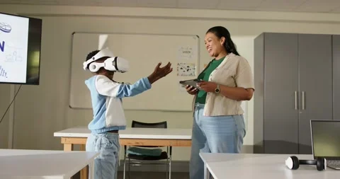African American teacher using tablet as teenage student VR headset making Stock Footage 336658351
