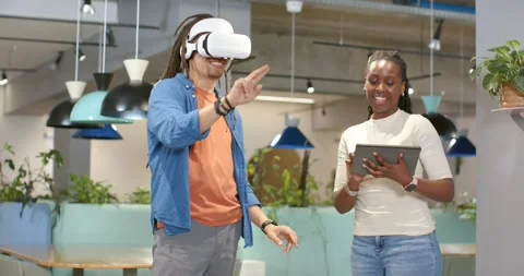 African American team at office testing VR man putting on headset gesturing Stock Footage 340257211