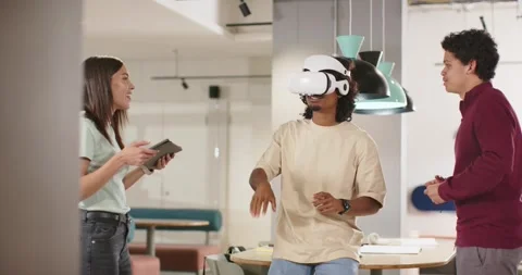 African American team testing VR at table, man placing headset, gesturing, woman Stock Footage 344340494