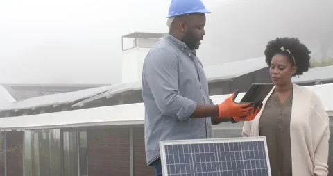 African American tech in hard hat with homeowner at roof check showing tablet Stock Footage 342363119