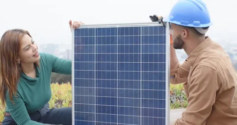 African American technician and client aligning solar panel on roof after Stock Footage 337886348