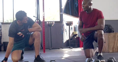African american trainer instructing white trainee in dumbbell pushups and Stock Footage 344534726
