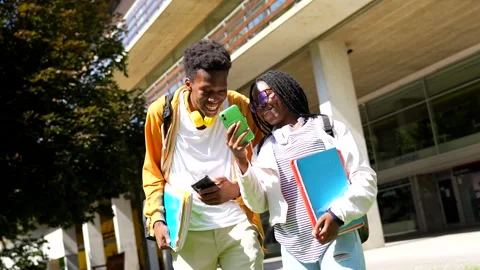 African american university friends using phones walking along the campus Stock Footage 282958866