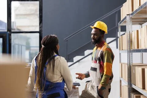 African american warehouse worker explaining colleague parcel packing 库存照片