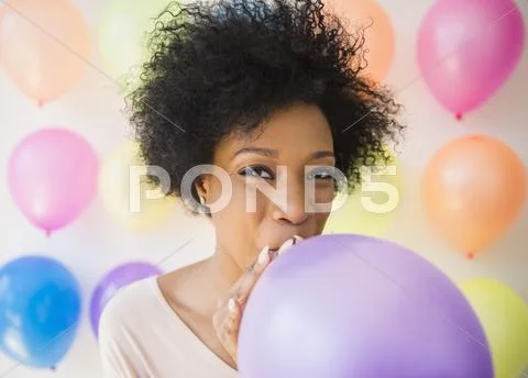 African American Woman Blowing Up Balloon For Party