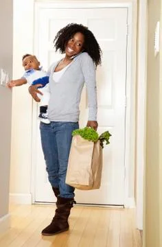 African American woman carrying bag of groceries. baby son and talking on phone Stock Photos