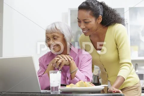 African American Woman Helping Mother With Laptop
