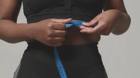 African american woman measure waistline by measuring tape, close-up. Slimming Stock Footage