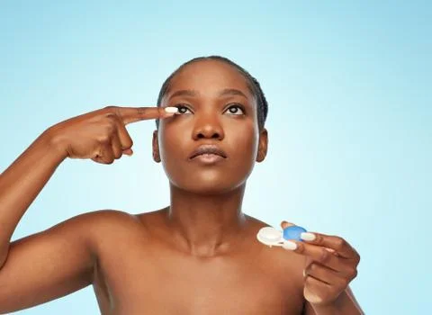 African american woman putting on contact lenses Stock Photos