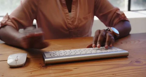 African American woman using computer mouse and keyboard at office desk Stock Footage 345571899