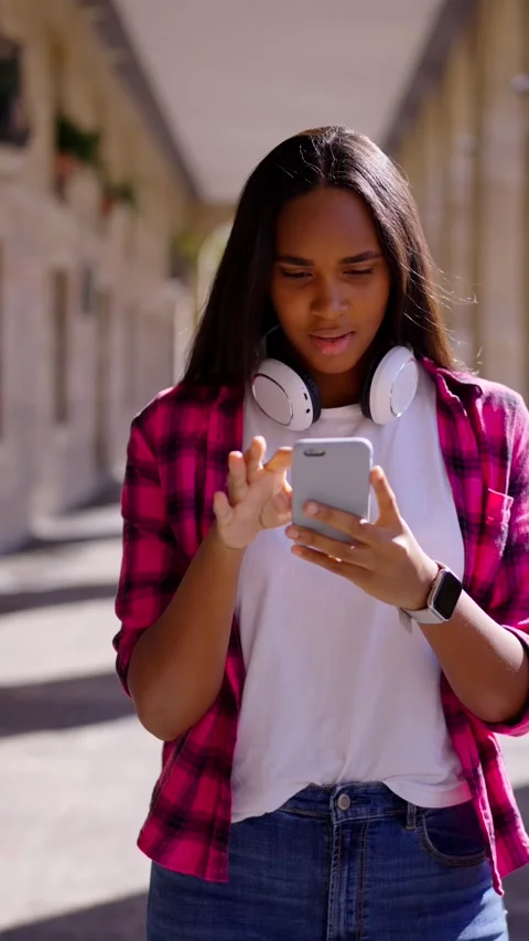 African American woman walking while using phone Stock Footage 252183166