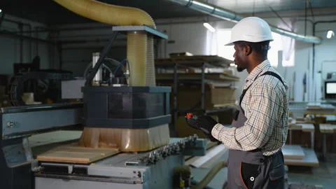 African American Worker Controls CNC Wood Cutting Machine Remotely Stock Footage 305604783