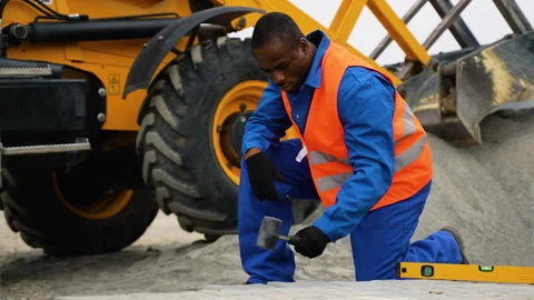 African American worker installing paving stones near heavy machinery Stock Footage 300899293