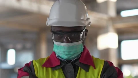 African american worker in mask stands at construction site and looks at camera Stock Footage 201693622