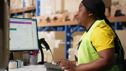 African american worker processing e-commerce cargo orders in warehouse setting Stock Footage 312836465