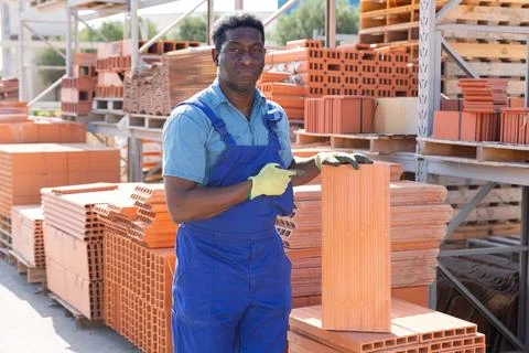African american worker stacking bricks in warehouse of building materials at Stockfoto's