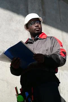 African american worker stands at construction site with work papers Stock Photos