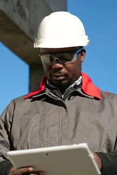 African american worker with tablet computer stands at construction site Stock Photos