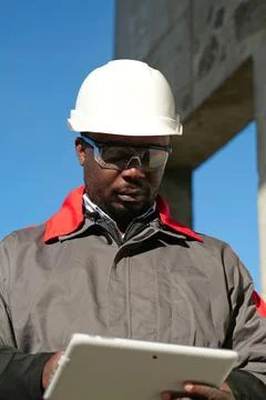 African american worker with tablet computer stands at construction site Stock Photos