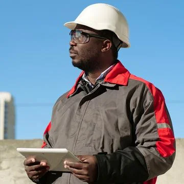 African american worker with tablet computer stands at construction site Stock Photos