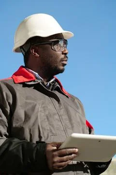 African american worker with tablet computer stands at construction site 스톡 사진