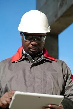 African american worker with tablet computer stands at construction site 스톡 사진