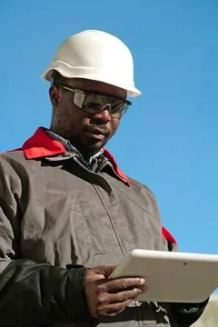 African american worker with tablet computer stands at construction site 库存照片