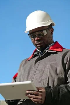 African american worker with tablet computer stands at construction site Stock Photos