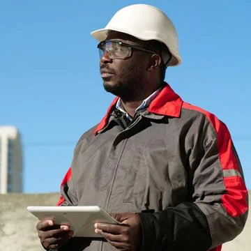 African american worker with tablet computer stands at construction site Stock Photos