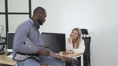 African-American worker taking a break and playing electric guitar in the office Stock Footage 233756586